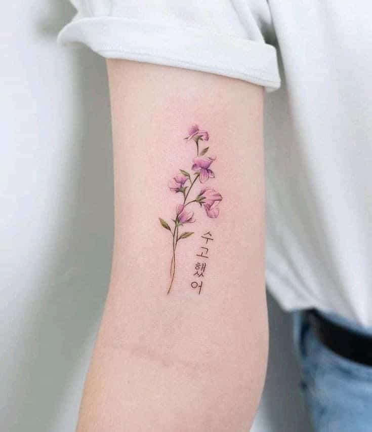 Delicate pink flower tattoo on arm with Korean text, elegant and minimalist design, showcasing body art expression.