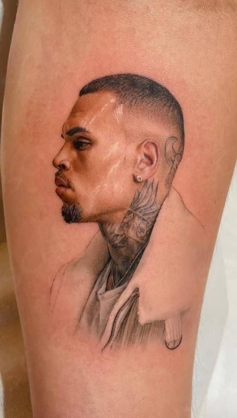 Tattoo of a man with short hair and tattoos on neck, wearing a white jacket, showcased on inner arm skin.