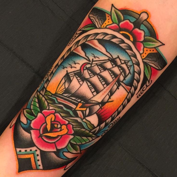 Colorful ship and rose tattoo featuring traditional maritime design elements on skin.