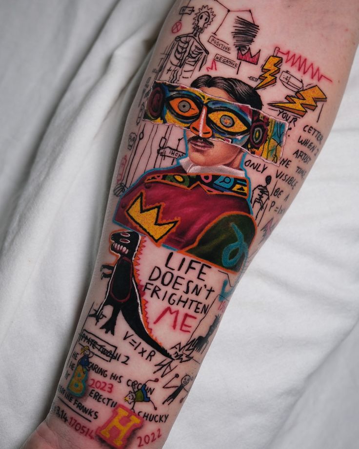 Colorful abstract tattoo on forearm featuring various artistic elements and text “Life Doesn’t Frighten Me.”