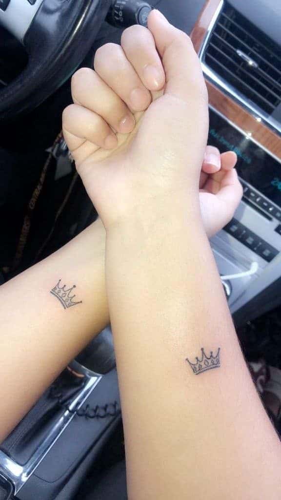 _ 19 Matching crown tattoos on forearms, symbolizing friendship or relationship, with car interior background. | Sky Rye Design Matching crown tattoos on forearms, symbolizing friendship or relationship, with car interior background.