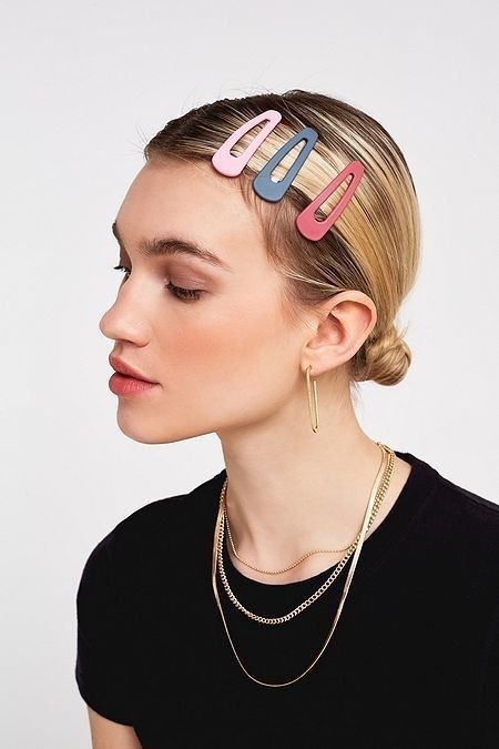 Profile of woman wearing colorful hair clips and gold jewelry, showcasing a chic and modern hairstyle.