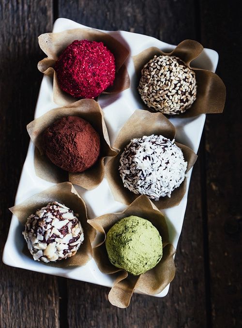 _ 2 Assorted truffles in a white tray, topped with seeds, coconut, cocoa, and more, on a rustic wooden table. | Sky Rye Design Assorted truffles in a white tray, topped with seeds, coconut, cocoa, and more, on a rustic wooden table.