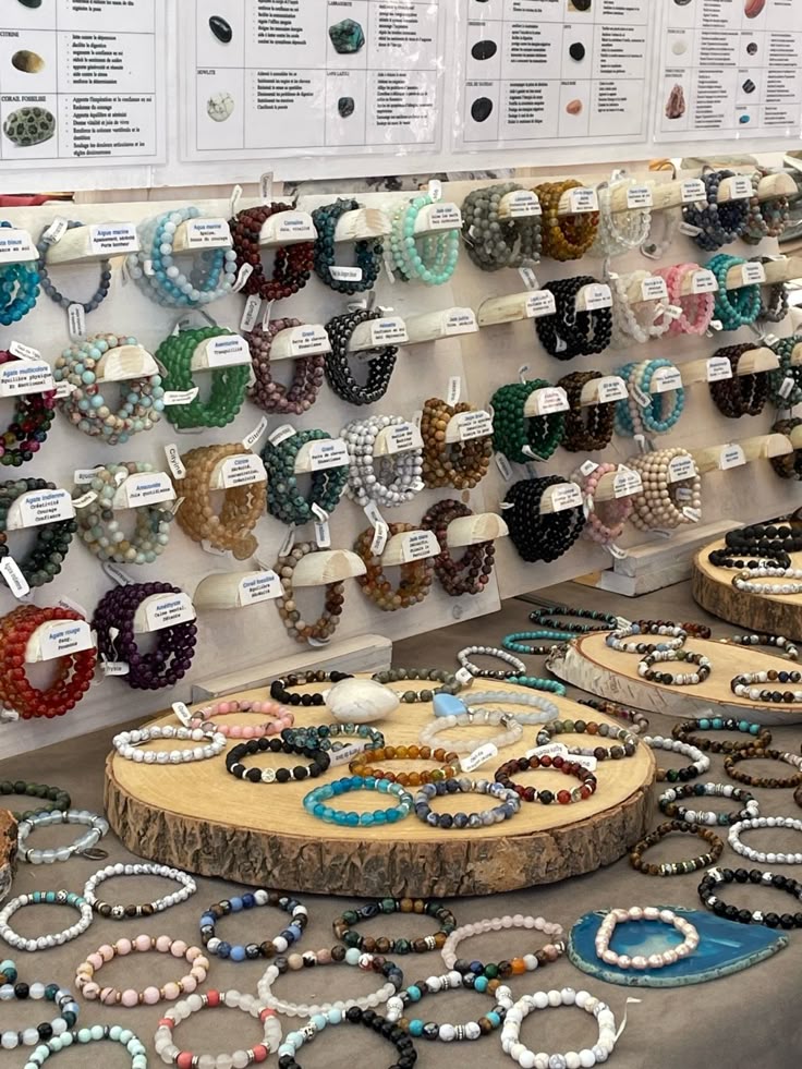 Colorful gemstone bracelets displayed on wooden stands at a market stall. Variety of crystals and designs available.