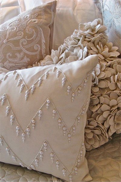 Elegant decorative pillows with intricate embroidery and floral patterns in soft beige tones.