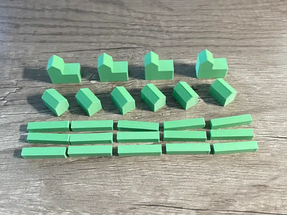 Green tabletop game pieces neatly arranged on a wooden surface for board game play.