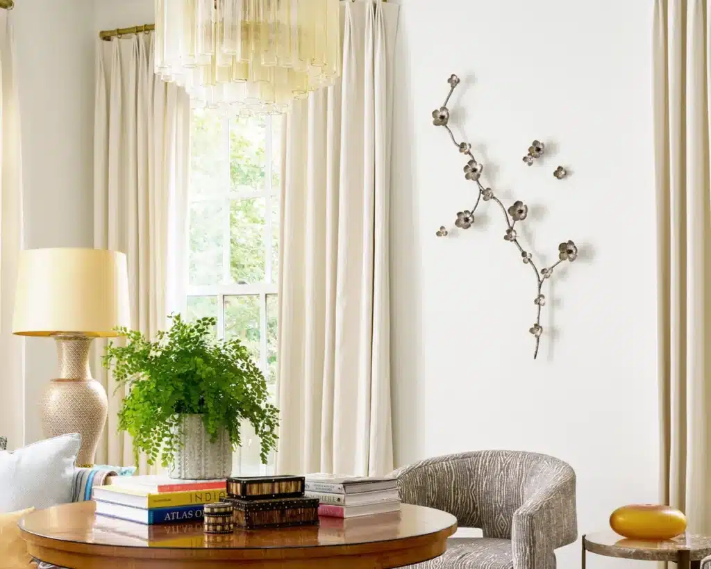 20248AriaWall0336-edit Elegant living room with modern chandelier, wall art, and cozy seating by a bright window. | Sky Rye Design Elegant living room with modern chandelier, wall art, and cozy seating by a bright window.