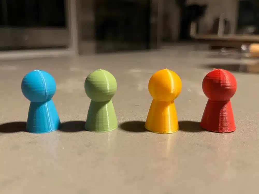 Colorful board game pieces on a table, featuring blue, green, yellow, and red cones.