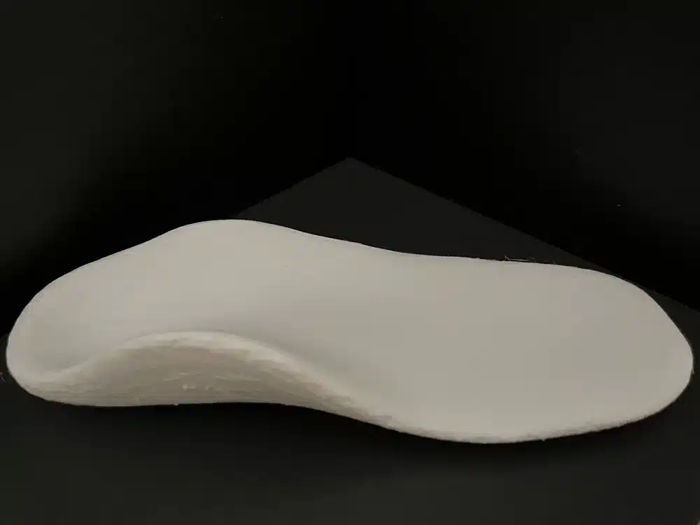 Orthopedic shoe insert on black background for foot support and comfort.