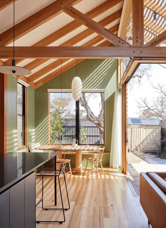 206-584x800 Modern sunlit dining area with wooden beams, green walls, and large windows opening to a garden view. | Sky Rye Design Modern sunlit dining area with wooden beams, green walls, and large windows opening to a garden view.