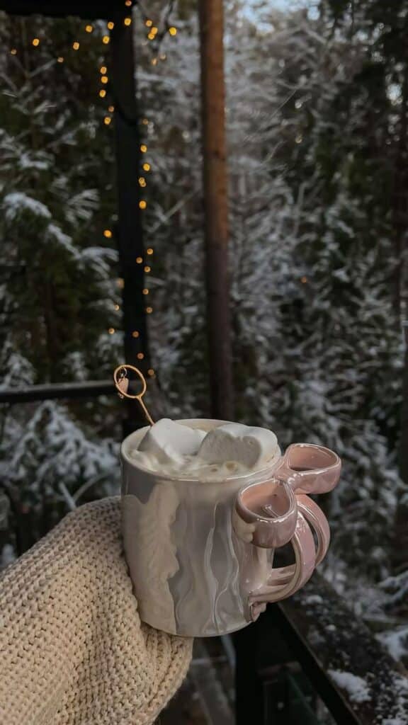 _ 21 Cozy winter scene with hot cocoa, marshmallows in heart shapes, and soft lights, held in a mitten-clad hand. | Sky Rye Design Cozy winter scene with hot cocoa, marshmallows in heart shapes, and soft lights, held in a mitten-clad hand.
