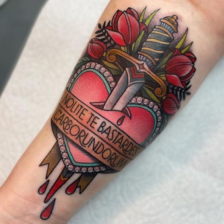 Heart and dagger tattoo with flowers and the phrase Nolite te bastardes carborundorum.