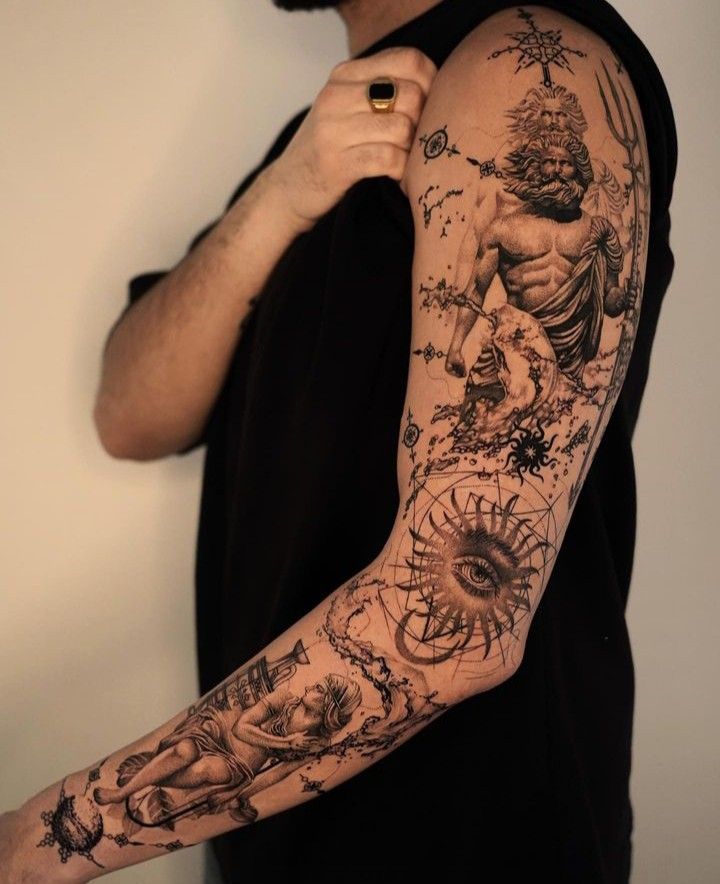 Arm adorned with intricate tattoo art featuring mythological and abstract designs.