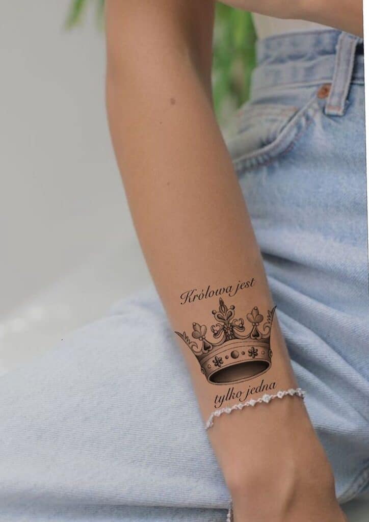 _ 21 Forearm with crown tattoo, Królowa jest tylko jedna in cursive, wearing jeans and bracelet. | Sky Rye Design Forearm with crown tattoo, Królowa jest tylko jedna in cursive, wearing jeans and bracelet.