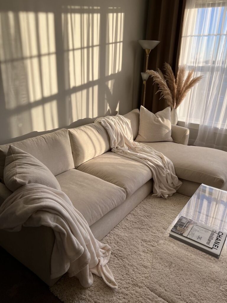 2104c306fa8dec156b00bfaa0e6ef7d9 Cozy living room with beige sofa, soft blanket, and pampas grass by sunny window. Perfect for relaxing moments. | Sky Rye Design Cozy living room with beige sofa, soft blanket, and pampas grass by sunny window. Perfect for relaxing moments.
