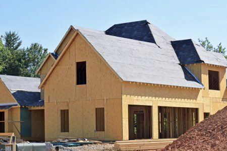 216c655b621a90ef01fbb50178c8688e House under construction with plywood walls and dark roof, surrounded by trees and dirt mound, under clear sky. | Sky Rye Design House under construction with plywood walls and dark roof, surrounded by trees and dirt mound, under clear sky.