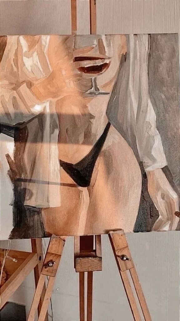 Painting of a sensual figure with a glass of wine, displayed on an easel in a softly lit room.