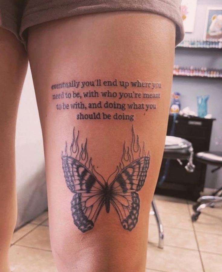 _ 24 Tattoo of inspirational quote above flaming butterfly on thigh, conveying destiny and purpose in life. | Sky Rye Design Tattoo of inspirational quote above flaming butterfly on thigh, conveying destiny and purpose in life.