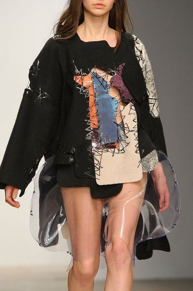 Model wearing avant-garde fashion with patchwork design and sheer accents on runway.