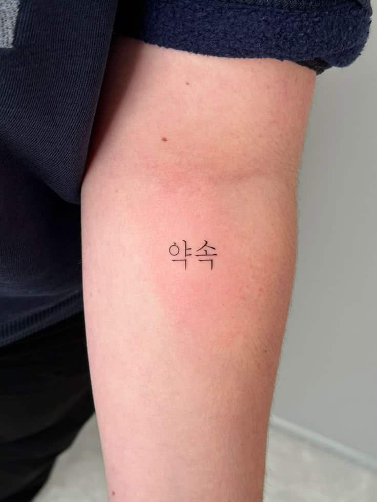 Arm tattoo with Korean word 약속, meaning promise, on forearm, symbolizing commitment or personal meaning.