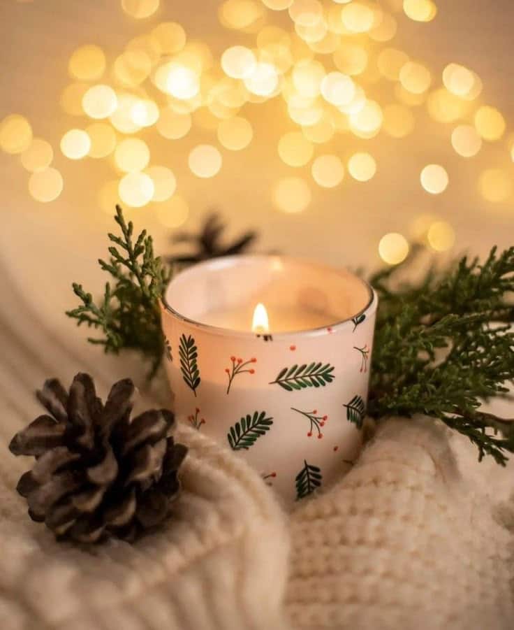 250c45b4-bdd5-4c05-a561-76ef8efbe560 Cozy candle with festive pine design, surrounded by greenery and a pinecone, glowing softly against a warm bokeh light backdrop. | Sky Rye Design Cozy candle with festive pine design, surrounded by greenery and a pinecone, glowing softly against a warm bokeh light backdrop.