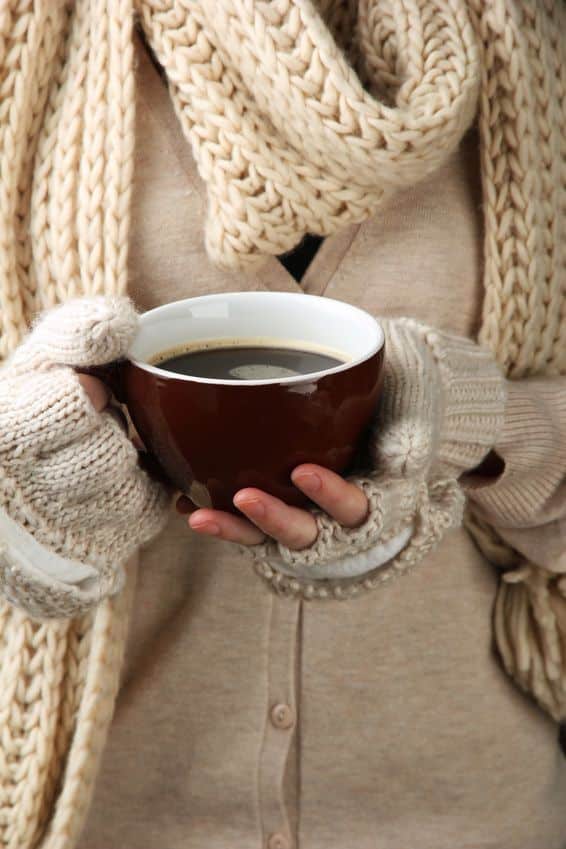255b9be7-90b8-4301-85a2-ce508fdfe66a Cozy woman in knitted scarf and gloves holding a warm cup of coffee. Perfect for winter warmth themes. | Sky Rye Design Cozy woman in knitted scarf and gloves holding a warm cup of coffee. Perfect for winter warmth themes.