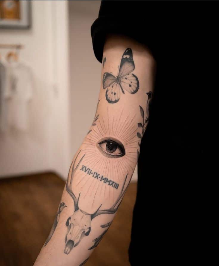 Arm tattoos featuring an eye, butterfly, antlers, and Roman numerals in minimalist black ink design. tattoo