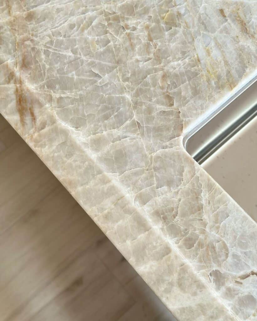 29026f950511cc16a4dd9048970ae3c4 Close-up of a polished marble countertop with intricate veining and a modern, sleek design in a kitchen setting. | Sky Rye Design Close-up of a polished marble countertop with intricate veining and a modern, sleek design in a kitchen setting.