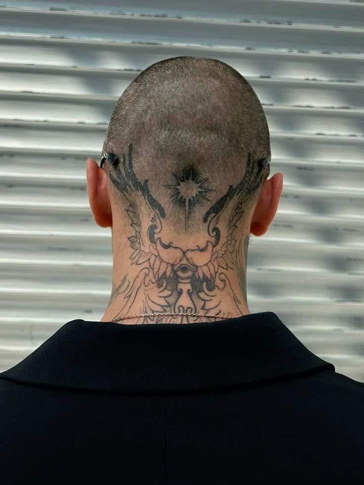 2a5bffc565d7fdfc762861847be0cc57 Back of head tattoo with intricate tribal design on a bald person, in front of a metallic background. | Sky Rye Design Back of head tattoo with intricate tribal design on a bald person, in front of a metallic background.