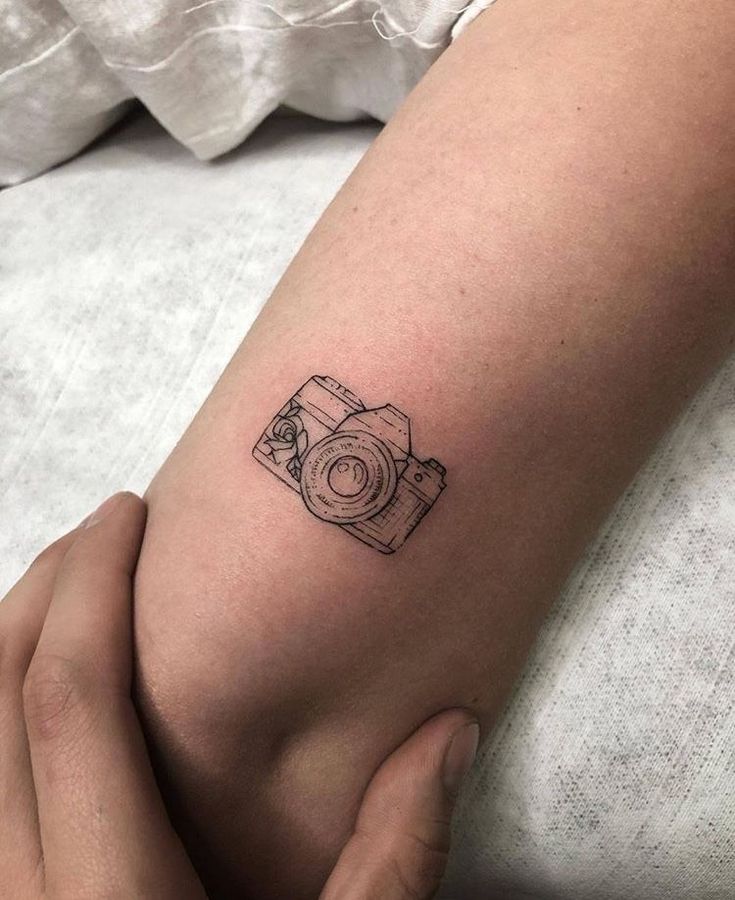 Camera tattoo on arm with a sleek, minimalist design, showcasing a passion for photography.