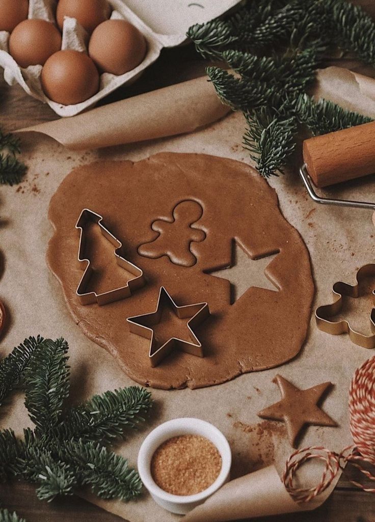 Christmas cookie dough with festive shapes, surrounded by baking ingredients and evergreen branches.