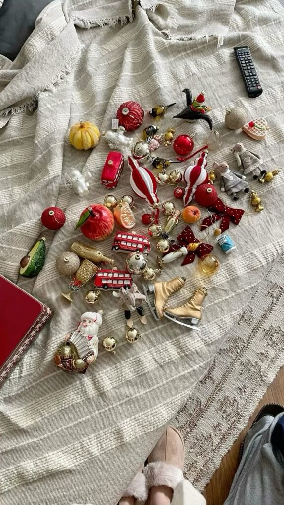 Christmas ornaments and decorations spread on a striped blanket, featuring Santa, ice skates, and festive shapes.