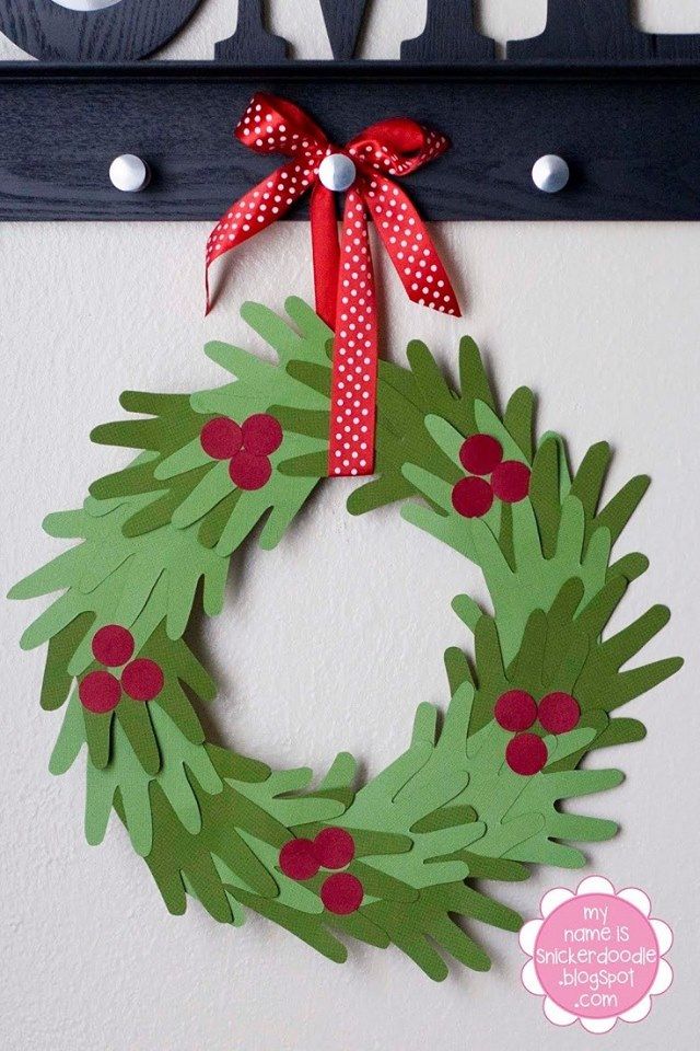 Paper Christmas wreath with red berries and bow, hanging on a hook. Perfect holiday decor idea.