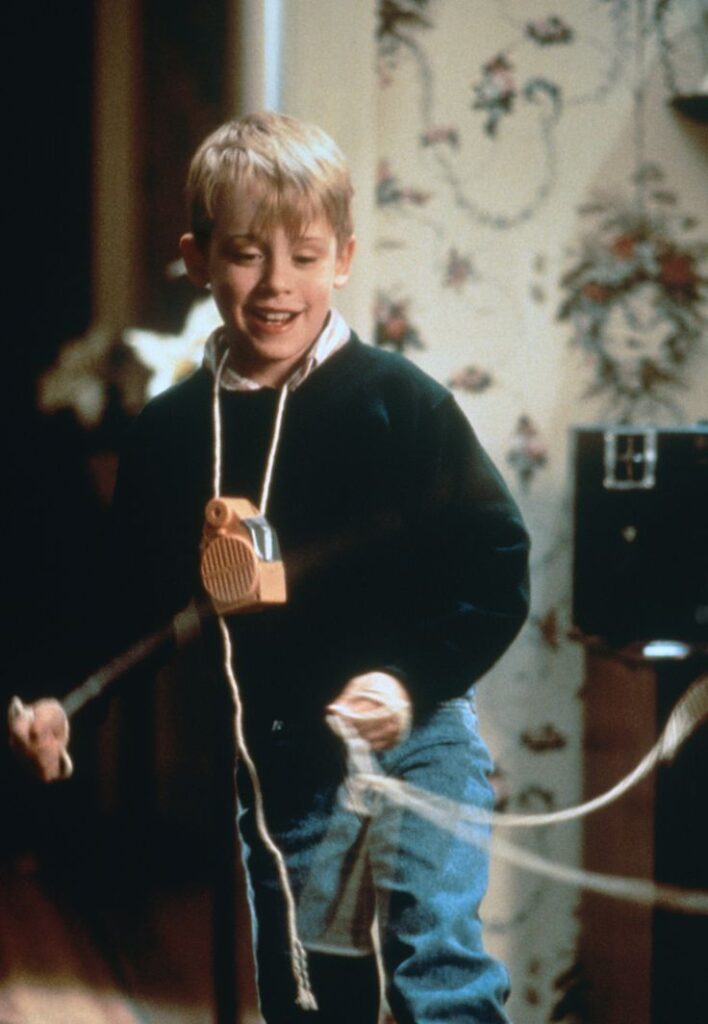 Child enjoying a jump rope indoors, wearing a toy suspended from their neck, with floral wallpaper as the background.