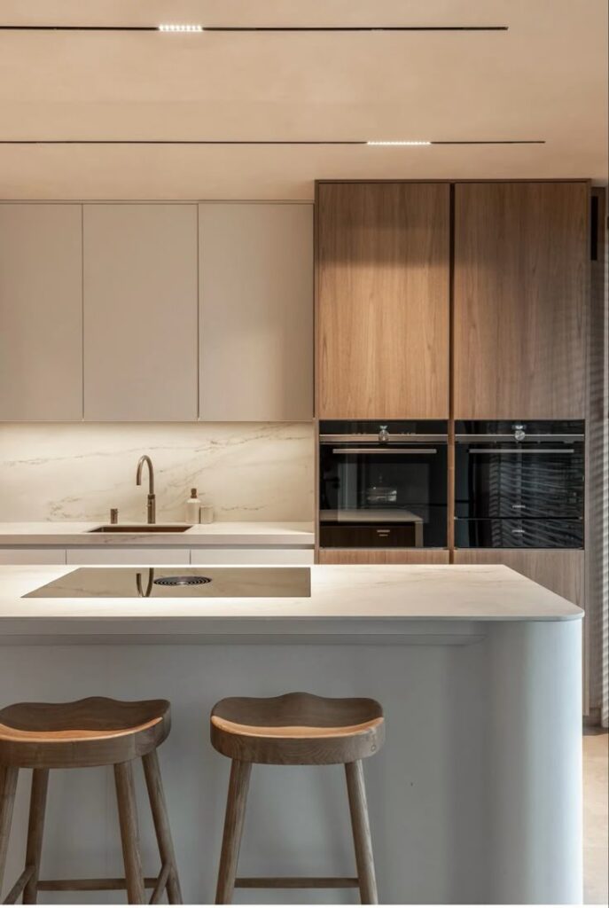 _ 3 Modern kitchen with marble countertop, sleek cabinets, and wood accents, featuring a stylish cooktop and stools. | Sky Rye Design Modern kitchen with marble countertop, sleek cabinets, and wood accents, featuring a stylish cooktop and stools.