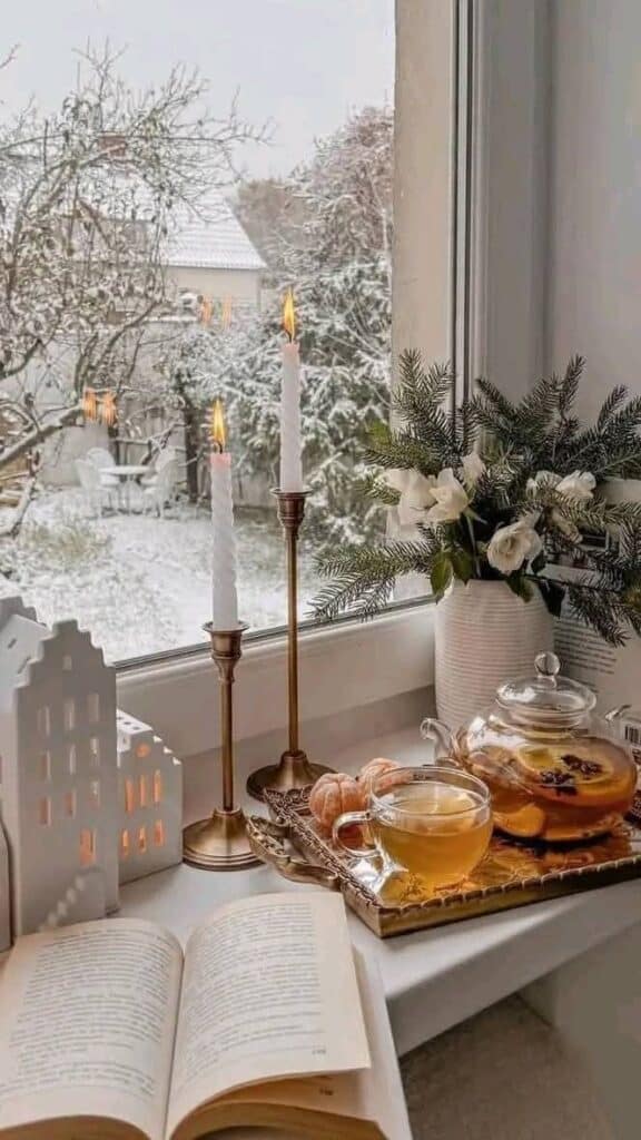 _ 3 Cozy winter scene with tea, candles, and flowers by a snowy window, creating a warm, inviting atmosphere for reading. | Sky Rye Design Cozy winter scene with tea, candles, and flowers by a snowy window, creating a warm, inviting atmosphere for reading.