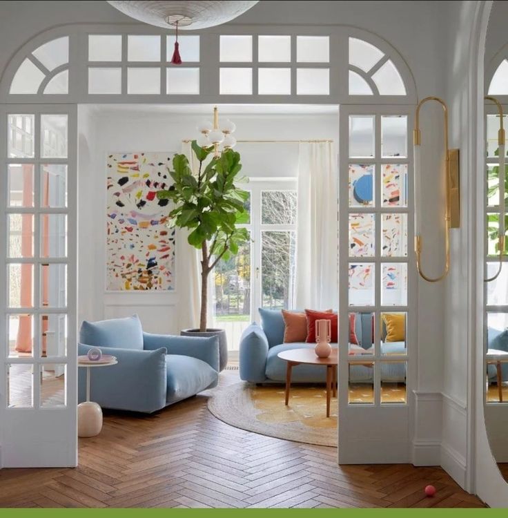 _ 3 Stylish modern living room with blue sofas, colorful decor, and large windows for natural light. | Sky Rye Design Stylish modern living room with blue sofas, colorful decor, and large windows for natural light.