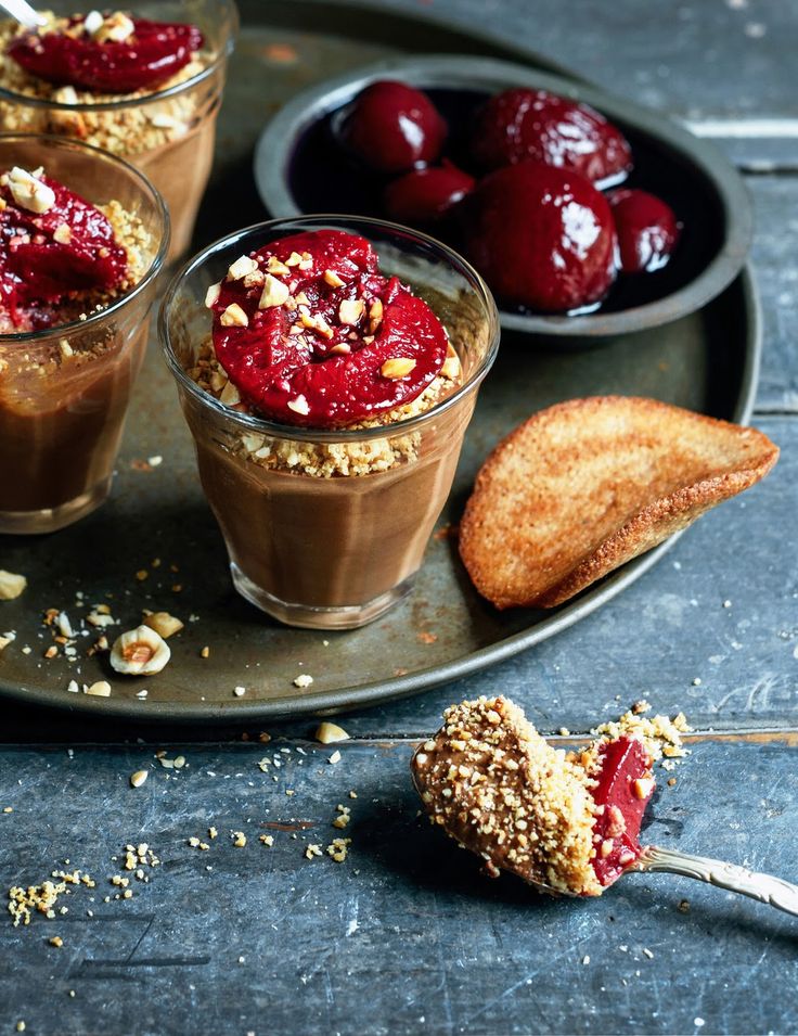 Chocolate mousse cups topped with red fruit and crushed nuts, served with toast on a rustic tray.