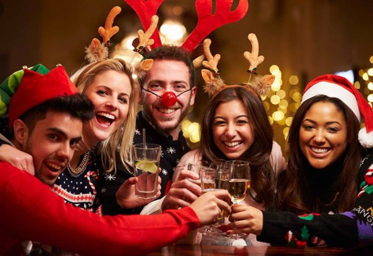 Friends celebrating Christmas at a party, wearing festive hats and raising glasses in a joyful toast.