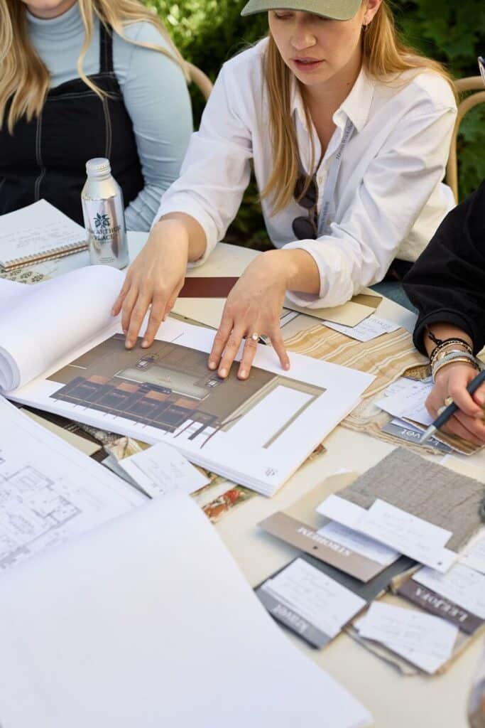 334e838785896419ae72ee42e84fb8b4 Design team reviewing interior project plans with fabric samples and architectural drawings on a table. | Sky Rye Design Design team reviewing interior project plans with fabric samples and architectural drawings on a table.
