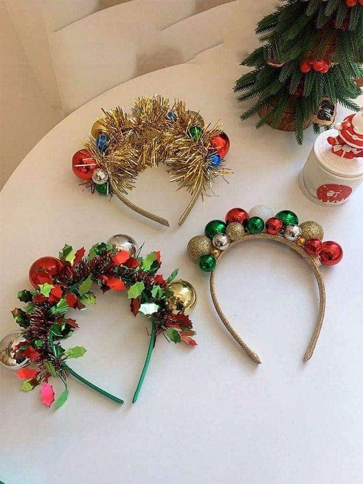 Festive holiday headbands with decorations on a table near a Christmas tree and festive jar.