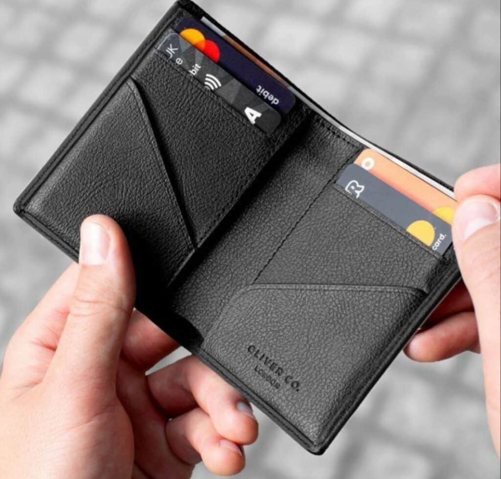381ee85c28f42a7afebcf687c0e84e28 Person holding an open black leather wallet displaying several credit cards. | Sky Rye Design Person holding an open black leather wallet displaying several credit cards.