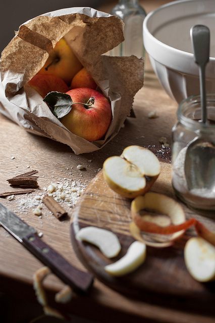 3d72d645-6519-4850-ae9d-c159d8a1bb6d Fresh apples in a paper bag on a wooden table, with sliced apples and baking ingredients nearby for a rustic kitchen scene. | Sky Rye Design Fresh apples in a paper bag on a wooden table, with sliced apples and baking ingredients nearby for a rustic kitchen scene.