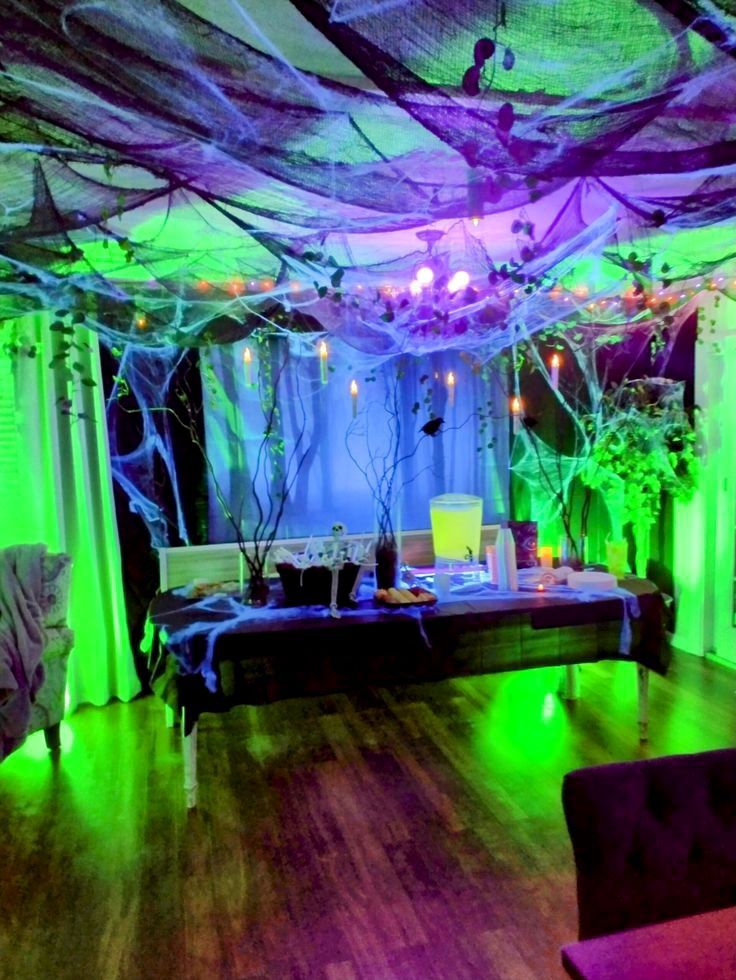 3edfdfd11689be7a41e4a6ea55635859 Spooky Halloween party setup with cobwebs, green-purple lighting, and eerie decor on a party table. | Sky Rye Design Spooky Halloween party setup with cobwebs, green-purple lighting, and eerie decor on a party table.