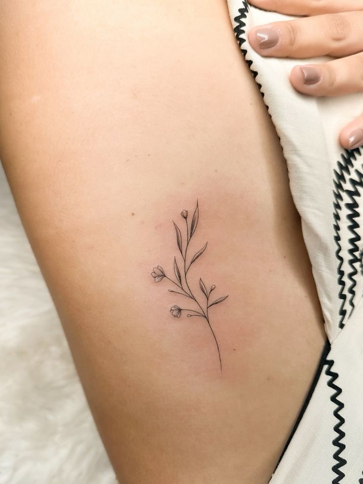 _ 4 Minimalist floral tattoo on skin, black linework, delicate design with small buds on a leg. | Sky Rye Design Minimalist floral tattoo on skin, black linework, delicate design with small buds on a leg.
