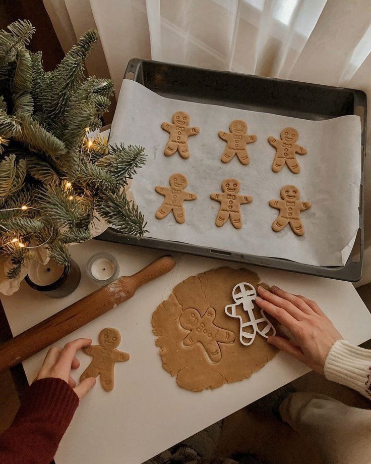 Baking gingerbread cookies with decorative Christmas tree and rolling pin in cozy kitchen setting.