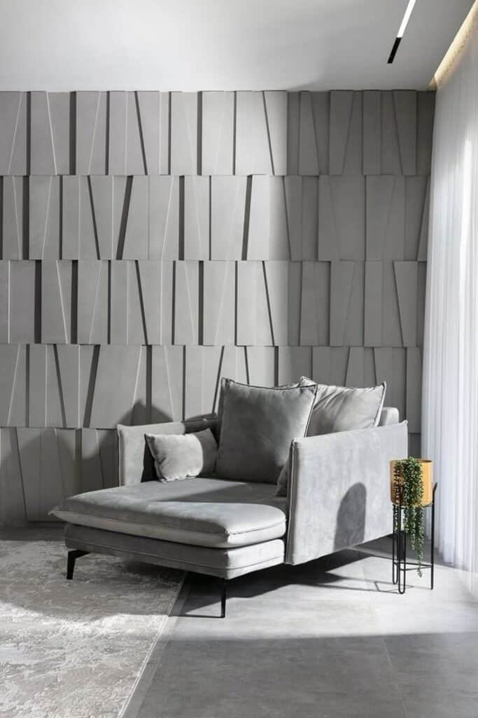 Modern gray sofa with textured wall in a sunlit living room, enhanced by patterned decor and greenery.