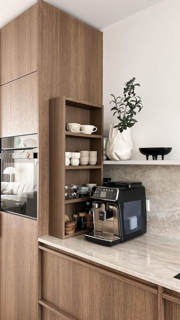 _ 4 Modern kitchen with a coffee machine, wooden shelves, cups, and decorative vase on a marble countertop. | Sky Rye Design Modern kitchen with a coffee machine, wooden shelves, cups, and decorative vase on a marble countertop.