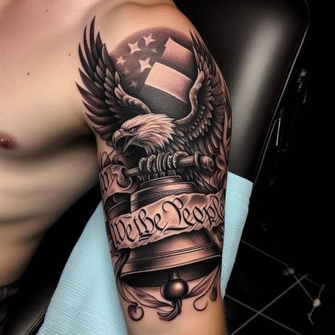 Patriotic tattoo featuring an eagle, American flag, and the phrase We the People on a person's upper arm.