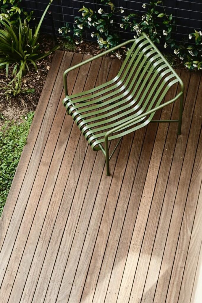 _ 4 Green metal chair on wooden deck beside lush garden plants. | Sky Rye Design Green metal chair on wooden deck beside lush garden plants.
